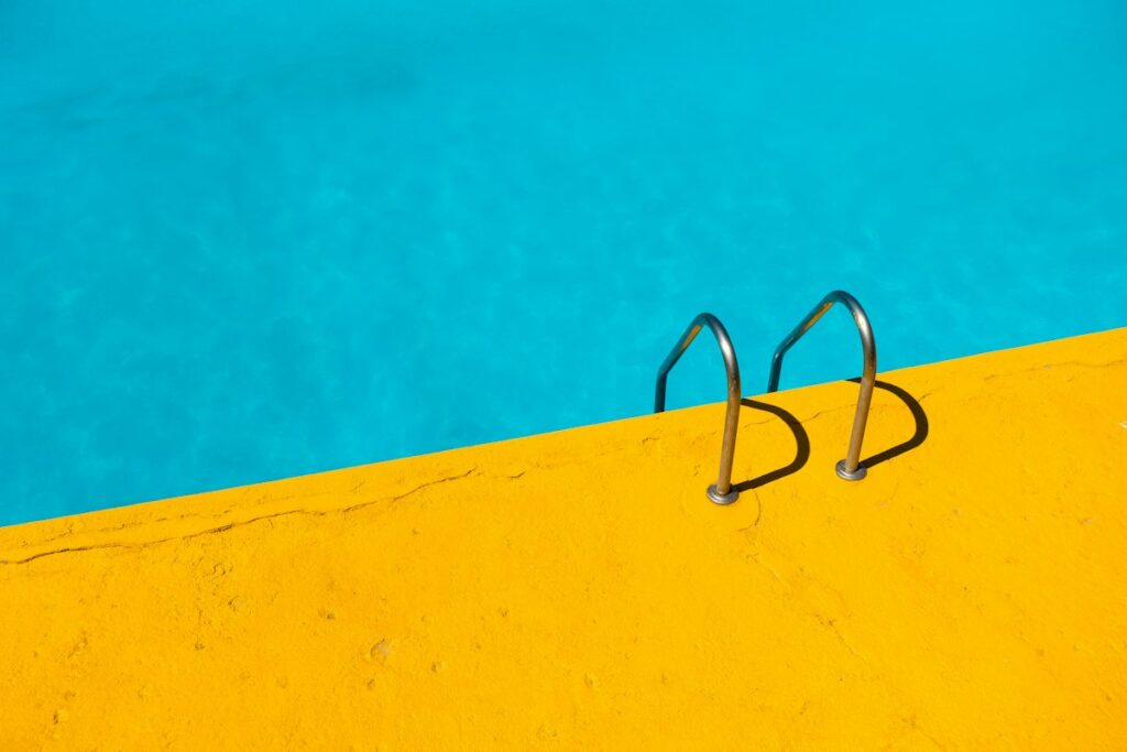 Piscine au sel : comment fonctionne l’électrolyse et comment bien l’entretenir Bord de piscine au sel avec échelle inox et eau turquoise